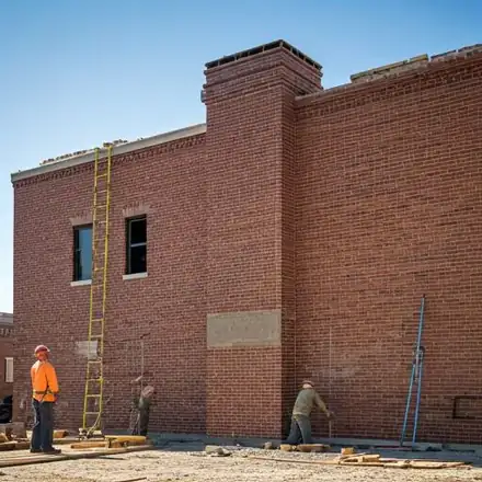Wide shot of a professional masonry team working on a large-scale commercial brick building in Corcoran