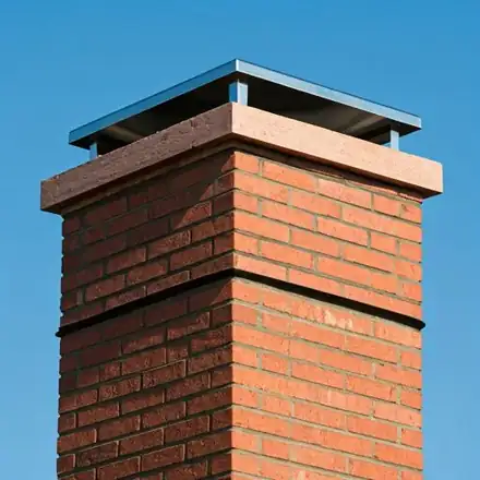 A perfectly restored brick chimney crown with clean mortar joints and a new stainless steel cap, set against a bright
